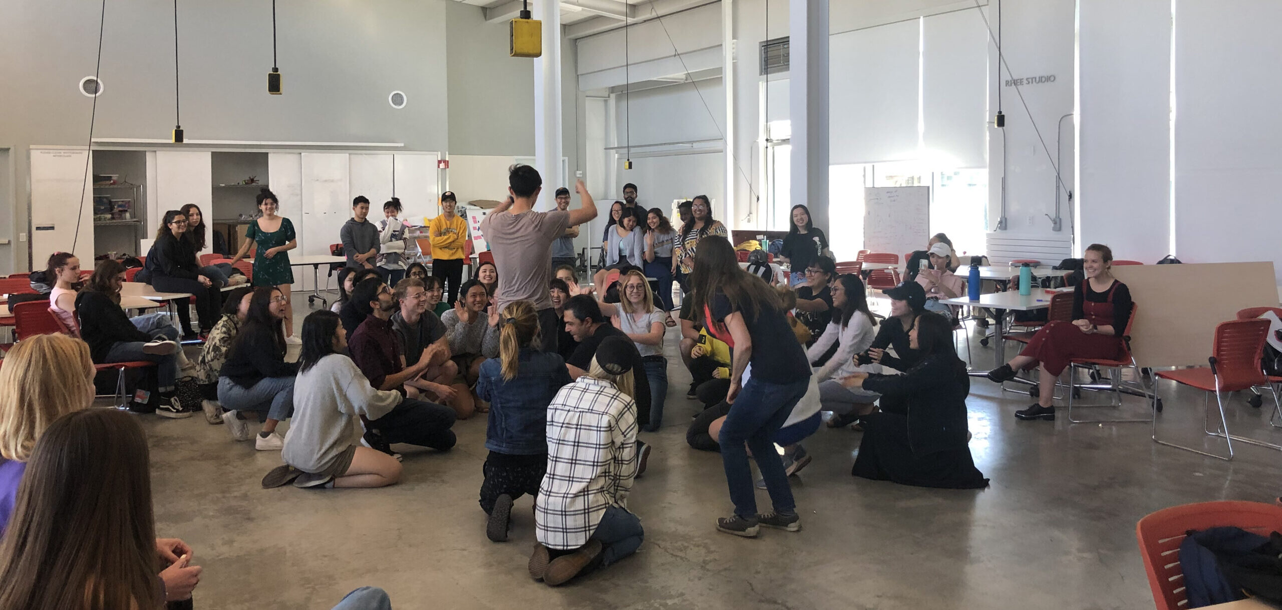 Students participating in a class, some seated and some standing