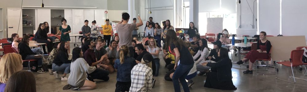 Students participating in a class, some seated and some standing